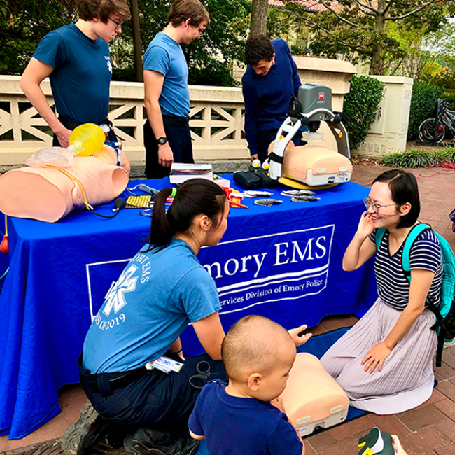 students with safety mannequins at Emory EMS table