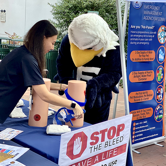 swoop mascot with student at a Stop the Bleed table