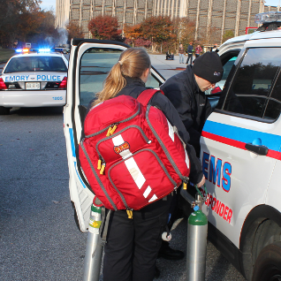EEEM personnel getting into marked car with red bag on woman's shoulder