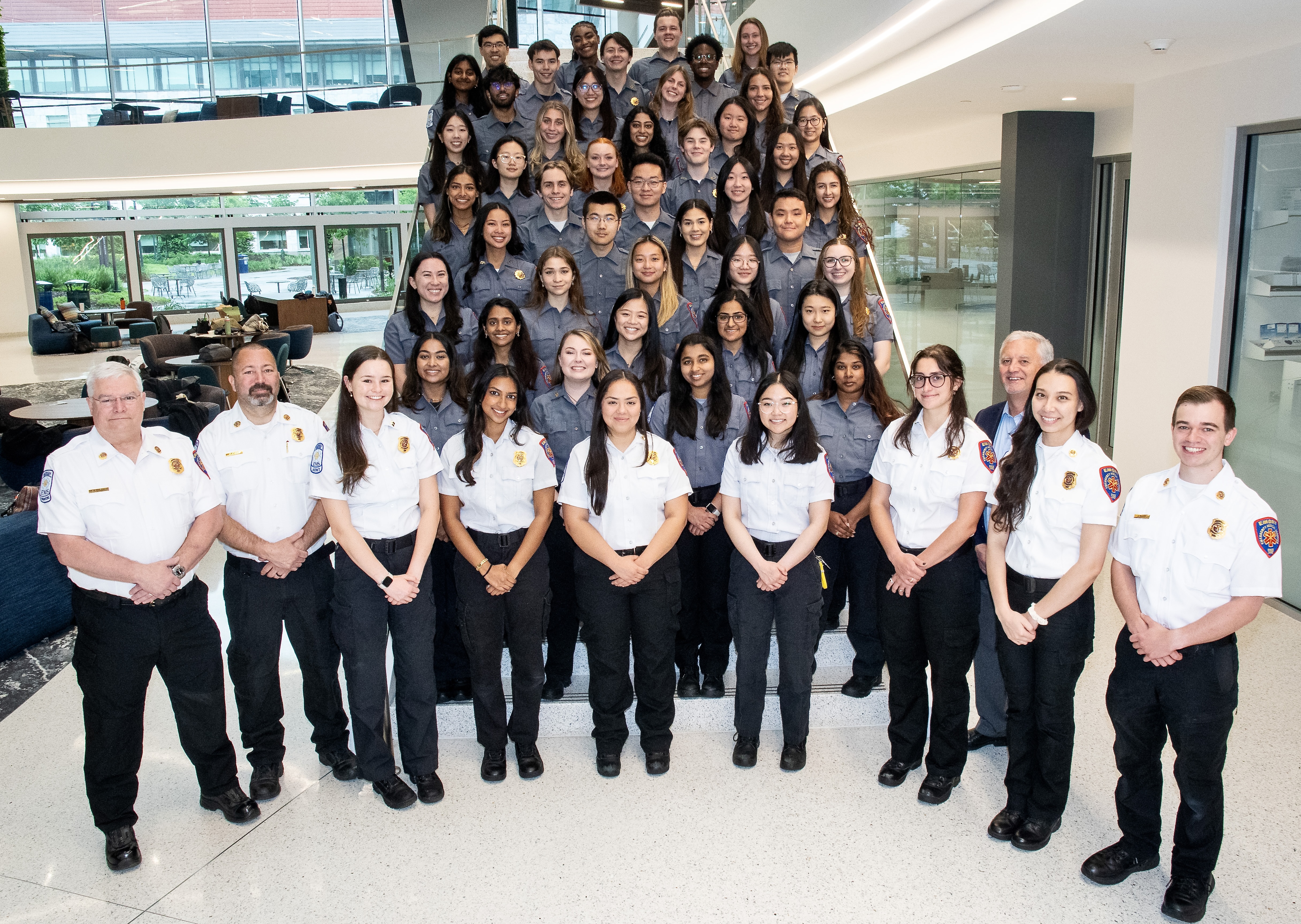 large group picture of Emory EMS teams in their uniforms with emergency vehicles behind them